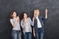 Three young girls pointing up on grey background Royalty Free Stock Photo