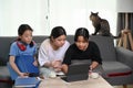 Three girls sitting on sofa and playing games online with  with computer tablet in living room. Royalty Free Stock Photo