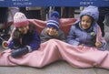 Three young girls staying warm while waiting for a parade, NY