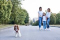 Three young girls, wearing blue jeans and white t-shirts, walking with small dog in city park in summer. Family fun leisure time Royalty Free Stock Photo