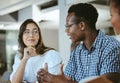 Three young happy businesspeople having a meeting while sitting at a table at work. Business professionals talking and Royalty Free Stock Photo