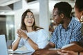 Three young happy businesspeople having a meeting while sitting at a table and working on a laptop at work. Business Royalty Free Stock Photo