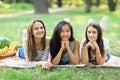 Three young happy multiracial women lying on grass in park