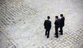 Three young jewish men wearing dark formal suits and a jewish kippah on their heads standing on an old stone pavement