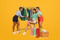 Three young ladies girlfriends shopping together online on yellow background Royalty Free Stock Photo