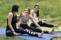 Three young laughing girls doing fitness on the grass. Athletic women stretch back of thigh Royalty Free Stock Photo