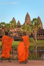 Three young monks at Angkor Wat, in traditional saffron colored robes, admiring the majestic temple.