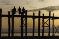 Three young monks on U-Bien bridge at sunset, silhouetted