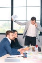 Three office workers for an interview, an angry man talking on the phone, and holding documents in his hand. Royalty Free Stock Photo