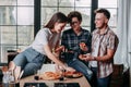 Three young people sitting around and eating pizza. Friends part Royalty Free Stock Photo