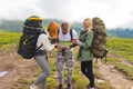 three young people of tourists friends: a guy and two girls blonde and redhead with backpacks on their back stand on a background Royalty Free Stock Photo