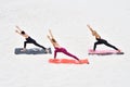 Three young slender women perform virabhadrasana yoga pose