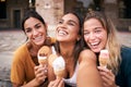 Three young smiling hipster women in summer clothes eating ice cream. Girls taking selfie self portrait photos Royalty Free Stock Photo