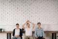 Three young tired guys sitting against a white brick wall waiting for something important. Royalty Free Stock Photo