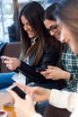 Three young woman using mobile phone at cafe shop. Royalty Free Stock Photo