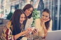 Three young women at coffee break using smart phone. Royalty Free Stock Photo