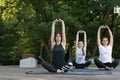 Three young women do exercises on outdoors. Yoga practice in the morning in park. Balance and harmony. Breathing practices Royalty Free Stock Photo