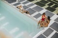 Young women drinking coctails and having fun by swimming pool Royalty Free Stock Photo