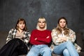 Three young women friends are sitting on the sofa at home gossiping about other women and people, talking about their lives and Royalty Free Stock Photo