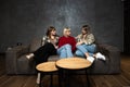 Three young women friends are sitting on the sofa at home gossiping about other women and people, talking about their lives and Royalty Free Stock Photo