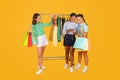 Three young women girlfriends shopping together on yellow background Royalty Free Stock Photo