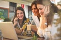 Three young women having conversation in cafe and using laptop. Royalty Free Stock Photo