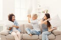 Three young women having pillow fight on sofa