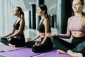 Three young women meditating in lotus pose during yoga class in health club. Women sitting on floor near window with city view Royalty Free Stock Photo