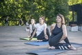 Three young women practice yoga in park. Exercise for flexibility. Girls are engaged in fitness outdoors Royalty Free Stock Photo