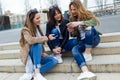 Three young women using a mobile phone in the street. Royalty Free Stock Photo