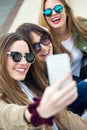 Three young women using a mobile phone in the street. Royalty Free Stock Photo