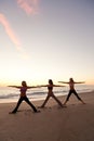 Three Women Practicing Yoga on Beach At Sunrise or Sunset Royalty Free Stock Photo