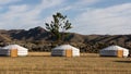 Three yurts stand in the steppe of central Mongolia in front of a huge towering mountain range in Mongolia, Asia. Royalty Free Stock Photo