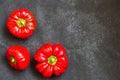 Threee red sweet peppers on dark background with copy space. Natural organic homegrown vegetable. Top view. Place for