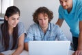 Threes company. three coworkers gathered around a laptop in the office. Royalty Free Stock Photo