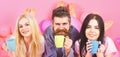 Threesome relax in morning with coffee. Lovers concept. Man and women, friends on smiling faces lay, pink background Royalty Free Stock Photo