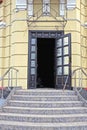 threshold with gray stone steps and metal handrails in front of an open black wood and glass door Royalty Free Stock Photo