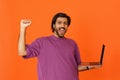 Thrilled indian guy trading on stocks, celebrating success on orange Royalty Free Stock Photo