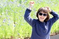 Thrilled young girl with blue sunglasses over spring cornflower field