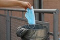 Throw surgical mask in public garbage can in city street. Hygienic mask puts in the trash