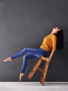 Throw your head back laughing. a happy young woman laughing while leaning back on a stool.