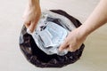 Throwing away single use medical face mask. Packing it in one time plastic bag before throwing it in trash.