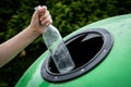 Throwing empty glass bottle into green recycle bin garbage container. Waste Sorting And Recycling Concept