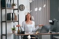 Throwing stickers up into air. Young beautiful woman in white clothes is in the office Royalty Free Stock Photo