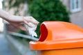 Throwing waste into a an orange trash can in the street