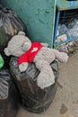 Thrown out stuffed bear toy ÃÂ«Me to youÃÂ» in a red sweater lies on garbage bags in the trash heap of Vidnoe