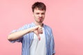 Thumb down, I don`t like it. Portrait of upset displeased brown-haired man showing dislike gesture. isolated on pink background Royalty Free Stock Photo