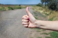 Thumb up is the symbol or sign of help or favor or hitchhike from hitchhiker on a road. Woman is showing her thumb for hitchhiking