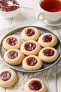 Thumbprint a buttery and crumbly vanilla cookie dough filled with delicious and tart raspberry jam closeup on the plate served