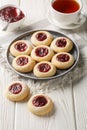 Thumbprint Christmas cookies filled with raspberry jam closeup on the plate served with tea on the wooden table. Vertical Royalty Free Stock Photo